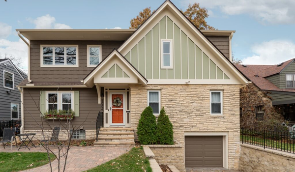 a two story home with green and brick exterior