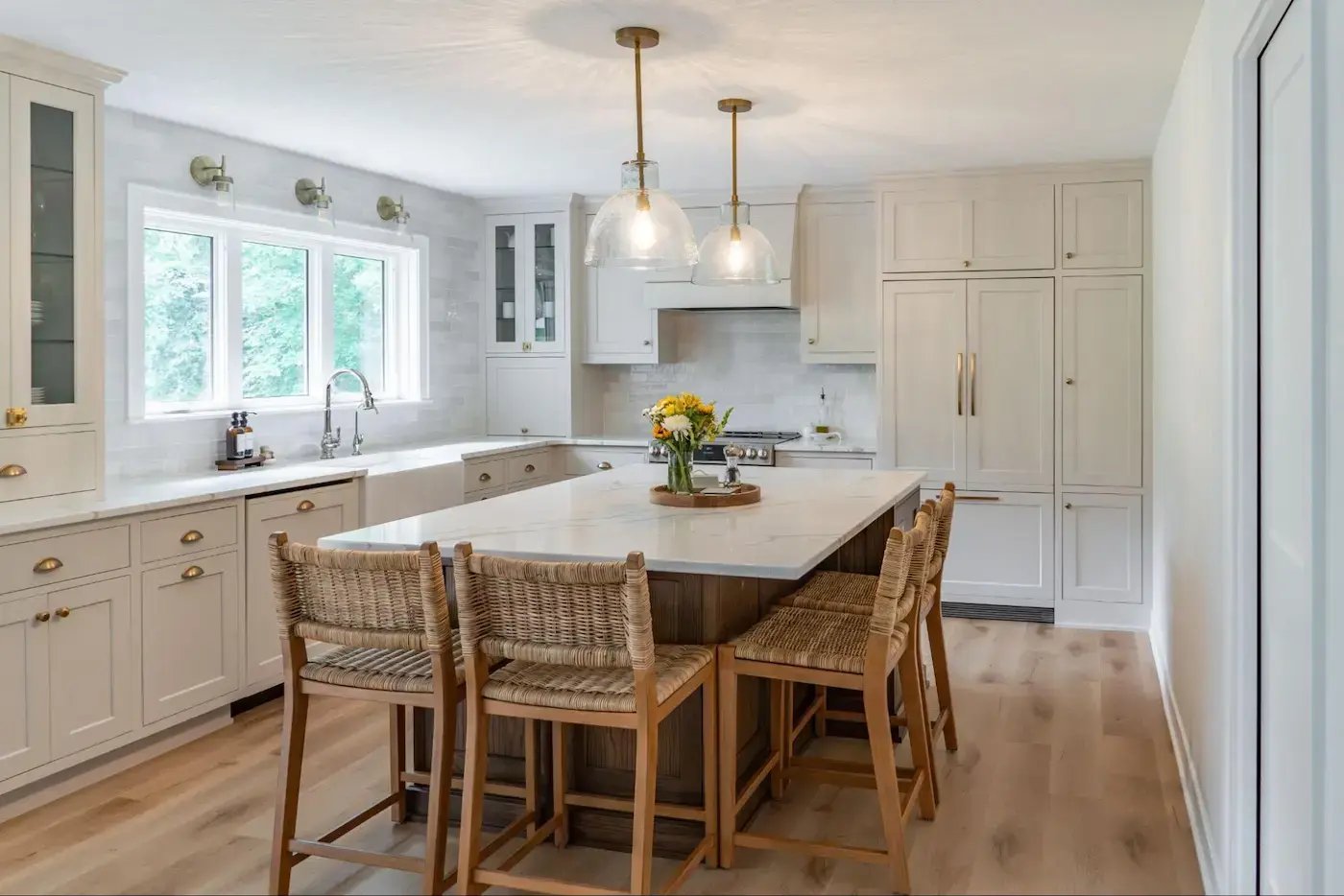 Titus project: modern and well-lit kitchen with light wooden and white cabinetry, a central island with a countertop and chairs, and a window providing natural light.