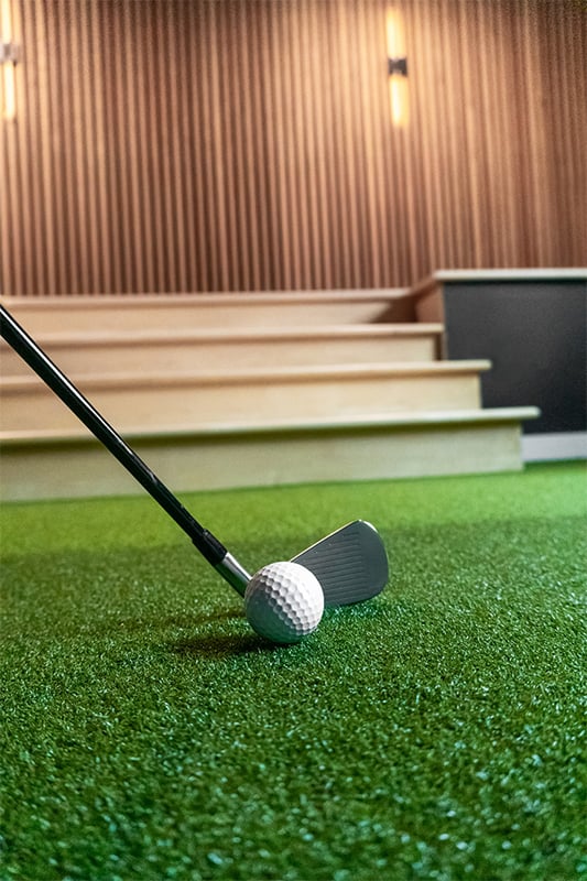 a golf simulator room with green grass and digital screen